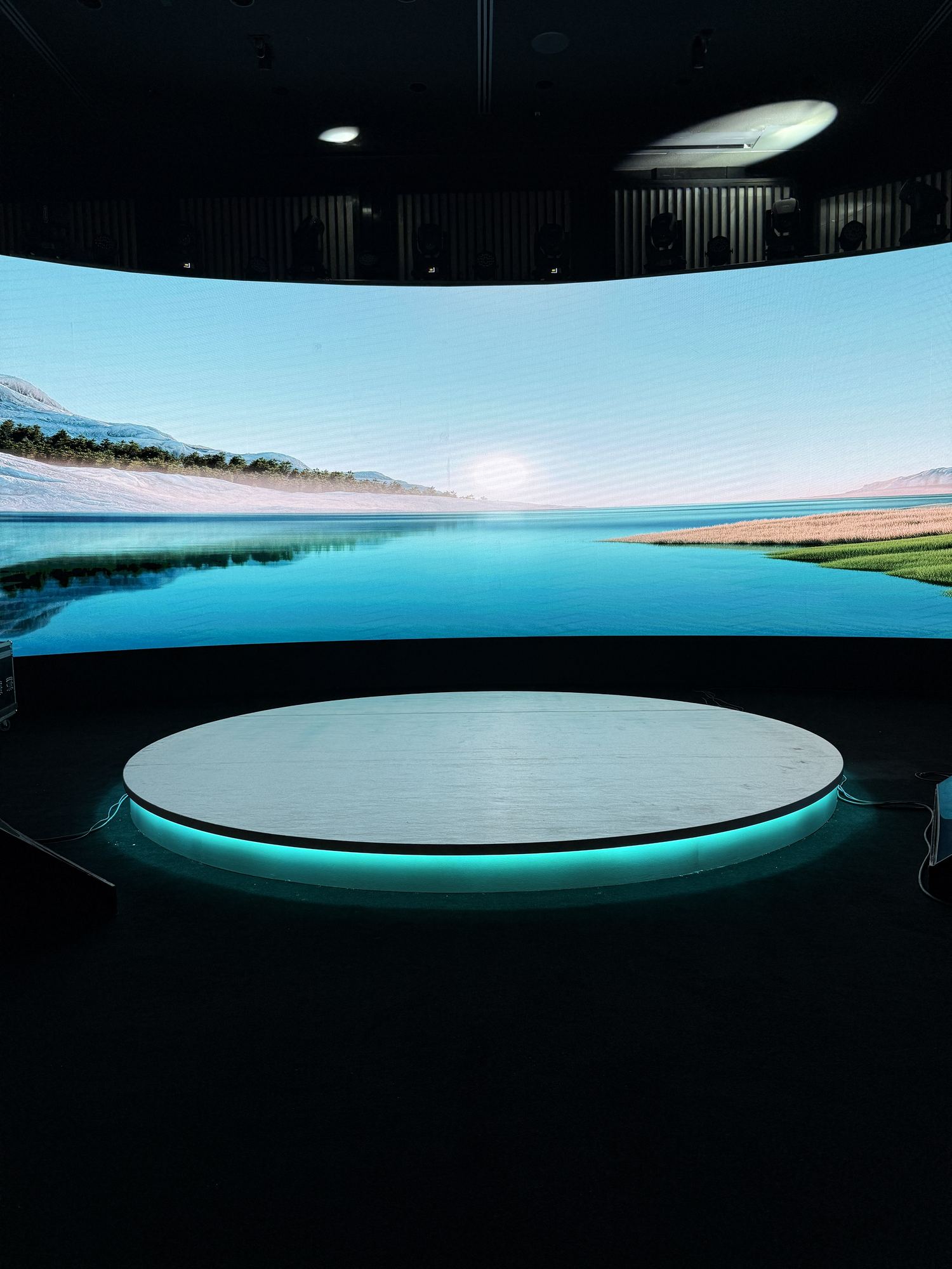 A completed convening room in darkness, with a curved wraparound projection wall and a single lit oval table